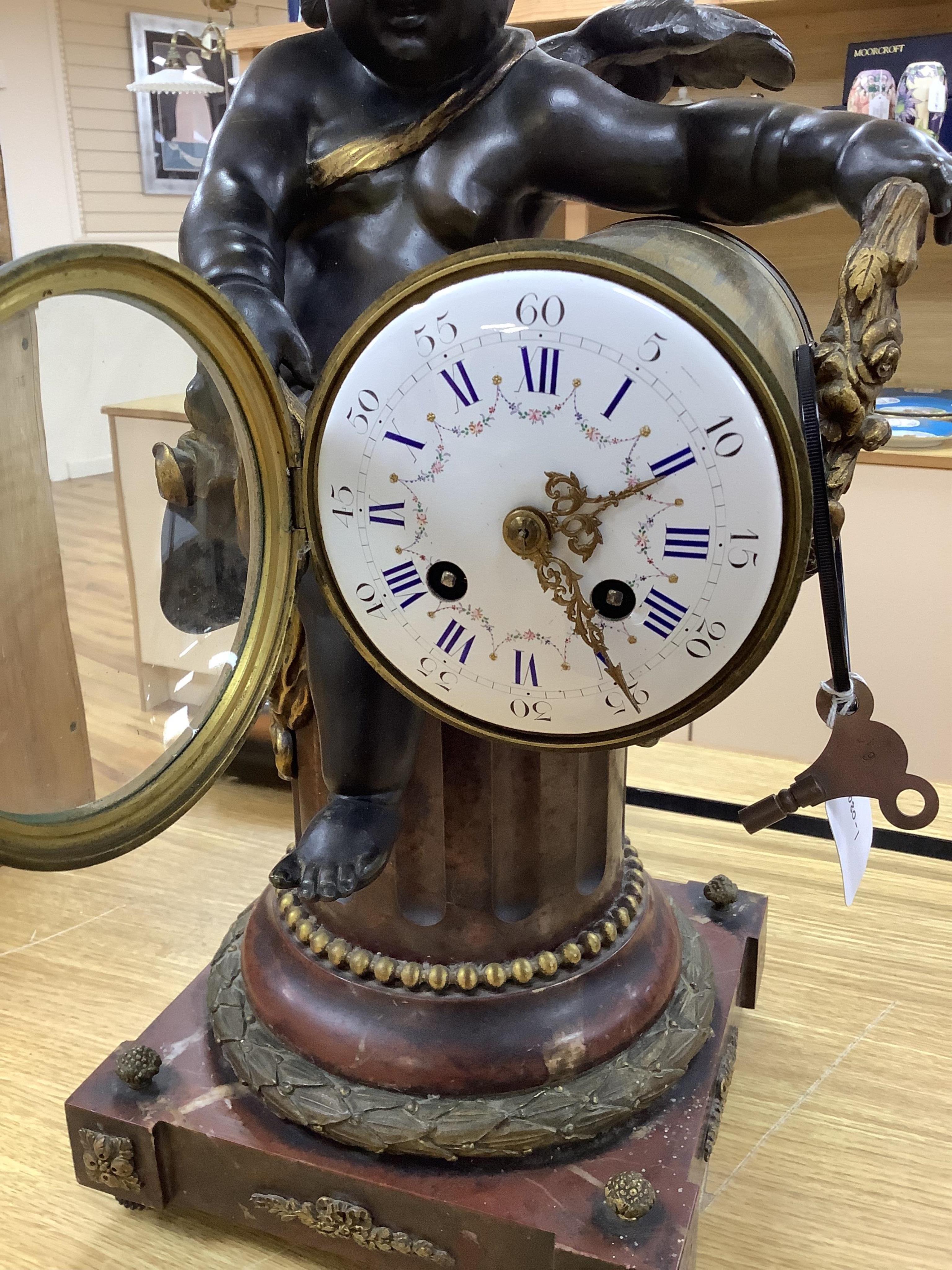 A large Louis XVI style bronze and rouge marble cherub clock, late 19th century, 56cm high